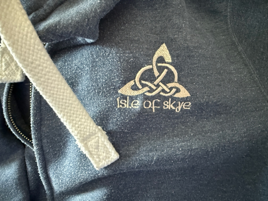 Close-up of the words Isle of Skye with a Celtic symbol on embroidered on a hoodie jacket with a zipper.